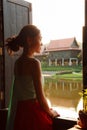 Young Beautiful Thai Asian woman dressing in vintage retro Traditional Thai costume looking out of window. Thailand Cultural and Royalty Free Stock Photo