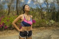 Young beautiful tired and breathless runner Asian woman exhausted and sweaty after hard running workout at trail road park in