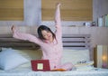 Young beautiful tired and sleepy Asian Japanese student girl stretching in bed after long hours studying late for college exam Royalty Free Stock Photo