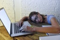 Young beautiful and tired student girl sleeping taking a nap lying on home laptop computer desk exhausted and wasted spending nigh Royalty Free Stock Photo