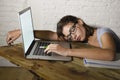 Young beautiful and tired student girl sleeping taking a nap lying on home laptop computer desk exhausted and wasted spending nigh Royalty Free Stock Photo