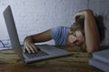 Young beautiful and tired student girl sleeping taking a nap lying on home laptop computer desk exhausted and wasted spending nigh Royalty Free Stock Photo