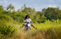 Young beautiful tourist or nomad traveler black afro American woman riding motorbike in tropical field wearing traditional Asian h