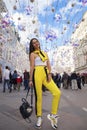Young beautiful tourist posing against the background of garlands on Nikolskaya street in the center of Moscow