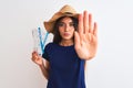 Young beautiful tourist woman holding boarding pass ticket over isolated white background with open hand doing stop sign with Royalty Free Stock Photo