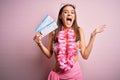 Young beautiful tourist woman on vacation wearing bikini and hawaiian lei holding boarding pass very happy and excited, winner Royalty Free Stock Photo