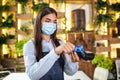 Young beautiful waitress with protective face mask making a credit card payment with card reader machine. Credit card swipe Royalty Free Stock Photo