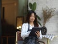 Young beautiful waitress taking an order on digital tablet in front of cafe