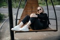 Young beautiful white girl is sitting on a park bench. Cute female lifestyle, portrait with soft focus. A thoughtful