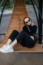 Young beautiful white girl is sitting on a park bench. Cute female lifestyle, portrait with soft focus. thoughtful