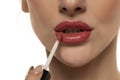 Young beautiful woman apply a lip gloss on her lips on white background Royalty Free Stock Photo