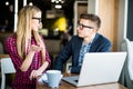 Young beautiful woman ask man at laptop with smile and discussing something with her coworker while standing at office Royalty Free Stock Photo