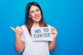 Young beautiful woman asking for psychical problem holding paper with not to suicide message pointing thumb up to the side smiling