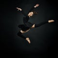 Young beautiful woman athlete gymnast in fly on black background