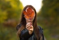 Young beautiful woman in autumn park holds a maple leaf Royalty Free Stock Photo