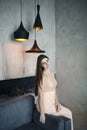 Young beautiful woman on background of gray wall and modern stylish lamps. New year, holidays concept