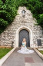 Young beautiful woman on a background of a stone old wall with a small vintage door entwined with ivy. Royalty Free Stock Photo