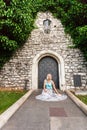 Young beautiful woman on a background of a stone old wall with a small vintage door entwined with ivy. Royalty Free Stock Photo