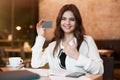 Young beautiful woman with bank card in her hand working outside office in laptop making payment transfer while drinking hot Royalty Free Stock Photo