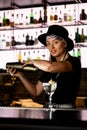 Young beautiful woman at bar holds steel shaker in hands and shakes it to mix all ingredients for cocktail