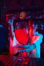 Young beautiful woman, bartender in modern bar, making delicious Aperol Spritz cocktail in neon. Decorating with dry Royalty Free Stock Photo