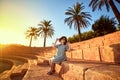 Young beautiful woman in beach hat sitting on the steps of an ancient amphitheater at sunny day in Bodrum, Turkey. Vacation Royalty Free Stock Photo