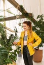 Young beautiful woman in beautiful clothes watering flowers and plants in her home garden. A girl is watering from a watering can Royalty Free Stock Photo