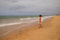 Young beautiful woman in bikini walking along the beach shore. The woman is enjoying her trip to a paradise beach while making Royalty Free Stock Photo