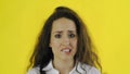 Young beautiful woman bites lip and stands in Studio with yellow Background.