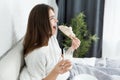 Young beautiful woman biting croissant and drinking milk for breakfast in bed in the morning Royalty Free Stock Photo