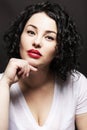 Young beautiful woman on a black background. Bright brunette with curly hair and red lipstick. Youth and natural beauty. Close-up Royalty Free Stock Photo