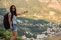 Young beautiful woman with black backpack hitchhiking standing on road. Beautiful young female hitchhiker by the road during vacat Royalty Free Stock Photo