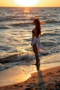 Young beautiful woman in a black bikini and white shirt on a tanned body on the beach admires the sunset. Soft selective focus Royalty Free Stock Photo