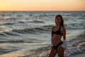 Young beautiful woman in black bikini and white shirt on a tanned body on the beach at sunset. Soft selective focus Royalty Free Stock Photo