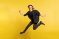 Young beautiful woman with black hat in studio on a yellow background, jumping. Royalty Free Stock Photo