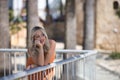 Young and beautiful woman, blonde with blue eyes and an orange dress, leaning on a railing with tender and dreamy look. Concept