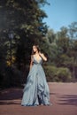 Young beautiful woman blue dress walking path in park. Royalty Free Stock Photo