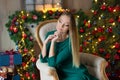 Young beautiful woman in blue elegant evening dress sitting on floor near christmas tree and presents on a new year eve. Interior Royalty Free Stock Photo