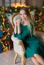 Young beautiful woman in blue elegant evening dress sitting on floor near christmas tree and presents on a new year eve. Interior Royalty Free Stock Photo