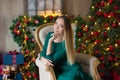 Young beautiful woman in blue elegant evening dress sitting on floor near christmas tree and presents on a new year eve. Interior Royalty Free Stock Photo