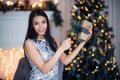 Young beautiful woman in blue elegant evening dress sitting on floor near christmas tree and presents on a new year eve Royalty Free Stock Photo