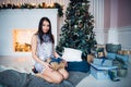 Young beautiful woman in blue elegant evening dress sitting on floor near christmas tree and presents on a new year eve Royalty Free Stock Photo