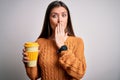 Young beautiful woman with blue eyes drinking cup of takeaway coffee over isolated background cover mouth with hand shocked with Royalty Free Stock Photo