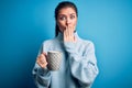 Young beautiful woman with blue eyes drinking mug of coffee over isolated background cover mouth with hand shocked with shame for Royalty Free Stock Photo