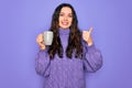 Young beautiful woman with blue eyes drinking mug of coffee over isolated purple background happy with big smile doing ok sign, Royalty Free Stock Photo