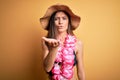 Young beautiful woman with blue eyes on vacation wearing bikini and hawaiian lei looking at the camera blowing a kiss with hand on Royalty Free Stock Photo