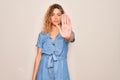 Young beautiful woman with blue eyes wearing casual denim dress over white background doing stop sing with palm of the hand Royalty Free Stock Photo