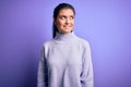 Young beautiful woman with blue eyes wearing casual turtleneck sweater over pink background looking away to side with smile on Royalty Free Stock Photo