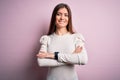 Young beautiful woman with blue eyes wearing casual white t-shirt over pink background happy face smiling with crossed arms Royalty Free Stock Photo