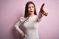 Young beautiful woman with blue eyes wearing casual white t-shirt over pink background Pointing with finger surprised ahead, open Royalty Free Stock Photo